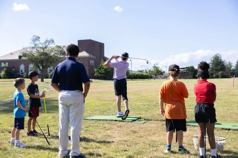 A coach leads a junior group on the range