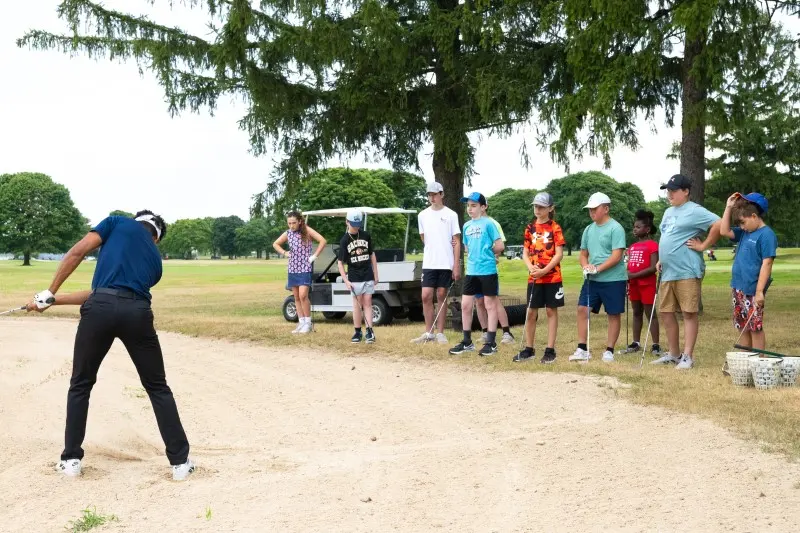 A coach demonstrates a bunker shot for juniors