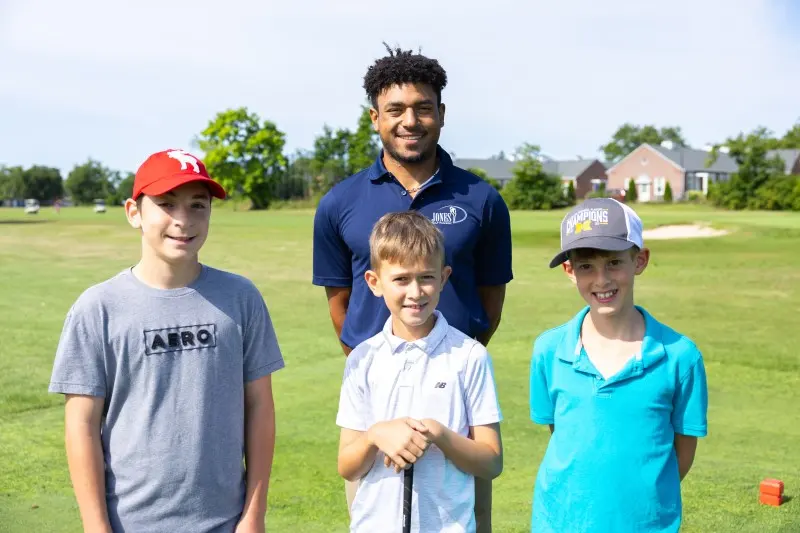 A coach with three junior golfers