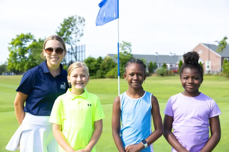 A coach with three junior girls on the course