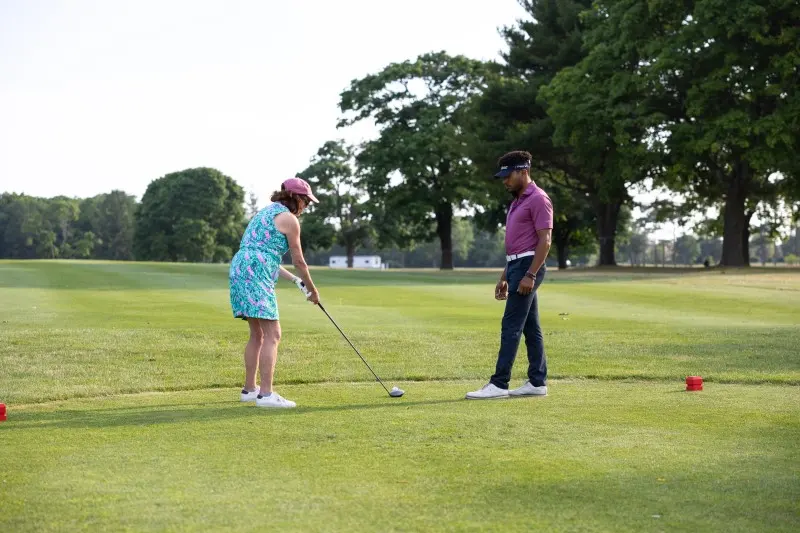 A coach works with a student on the fairway