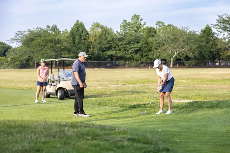 An instructor and student beside a cart on the course